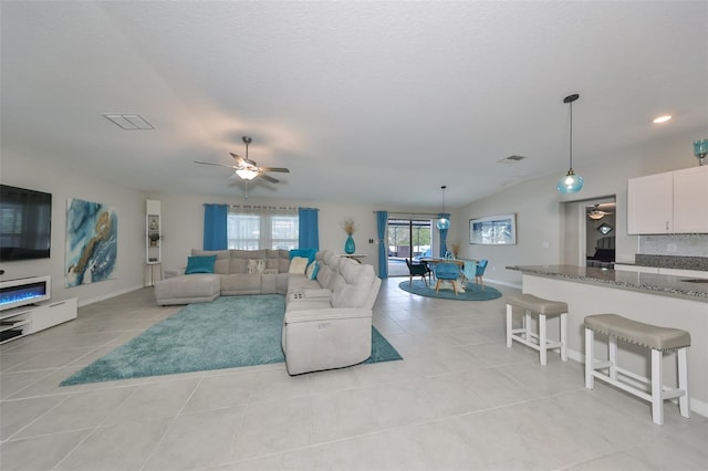 tiled living room with a textured ceiling, ceiling fan, and lofted ceiling