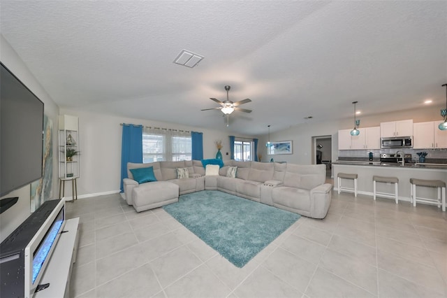 living room with light tile patterned floors, a textured ceiling, vaulted ceiling, and ceiling fan