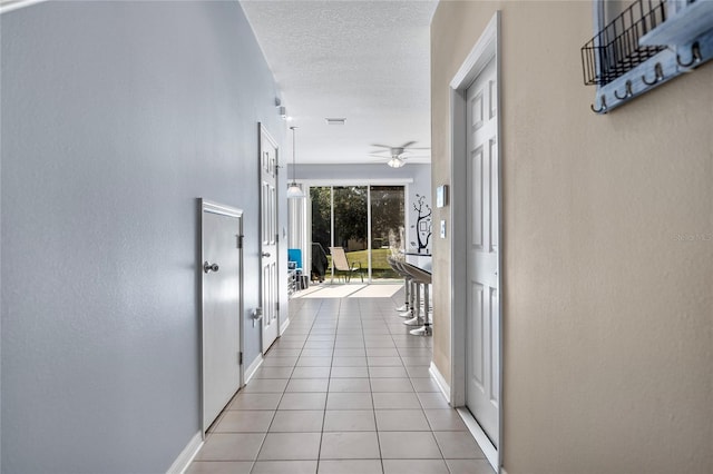 corridor with light tile patterned floors and a textured ceiling