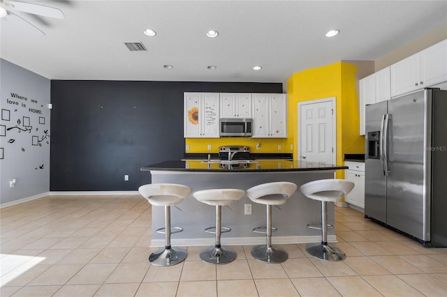 kitchen featuring a breakfast bar area, a kitchen island with sink, white cabinets, and appliances with stainless steel finishes