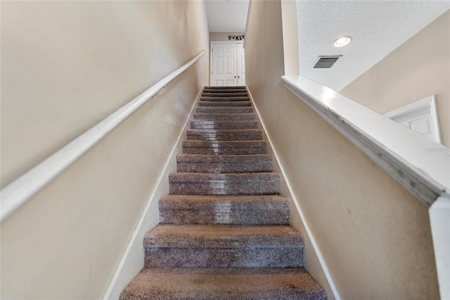 staircase featuring a textured ceiling