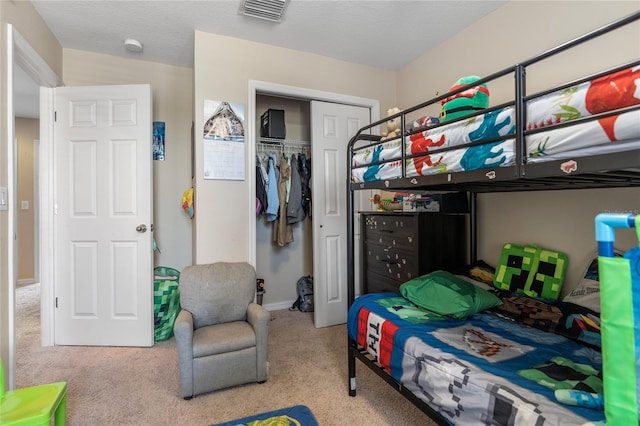 bedroom with a textured ceiling, light carpet, and a closet