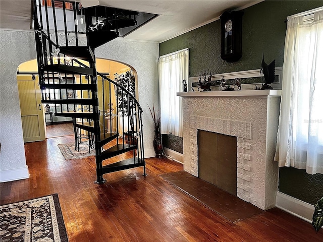 interior space featuring hardwood / wood-style flooring, a brick fireplace, and crown molding