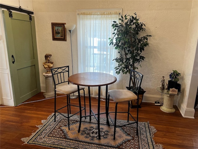 dining area featuring a barn door and dark wood-type flooring