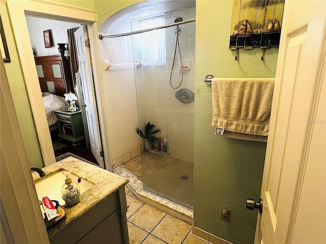 bathroom with tile patterned floors, vanity, and tiled shower