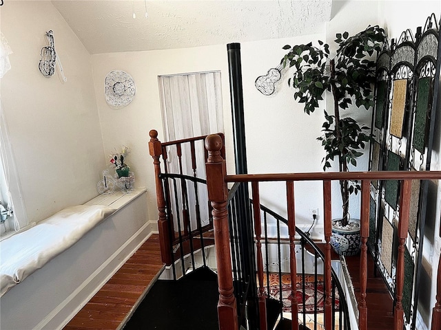 staircase with hardwood / wood-style floors and a textured ceiling