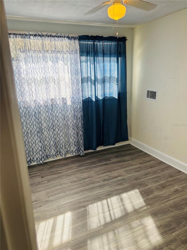 empty room with a textured ceiling, hardwood / wood-style flooring, plenty of natural light, and ceiling fan