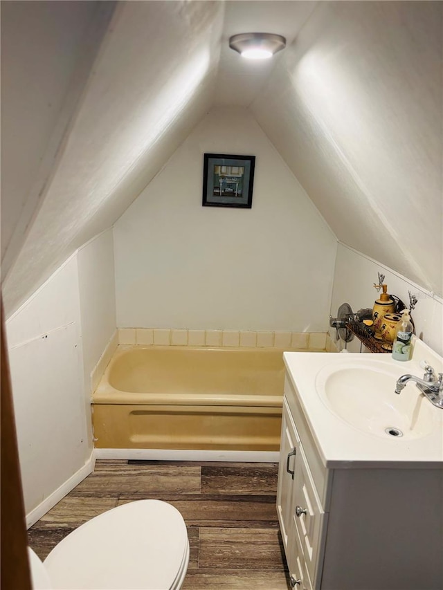 bathroom with vanity, wood-type flooring, a tub, and lofted ceiling