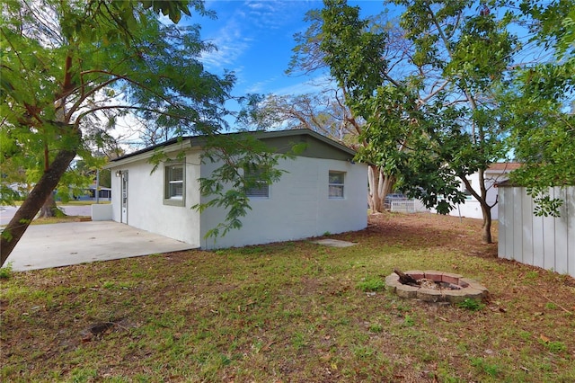 view of side of property featuring a patio area and a fire pit