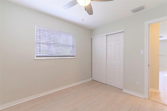 unfurnished bedroom featuring ceiling fan, a closet, and light wood-type flooring