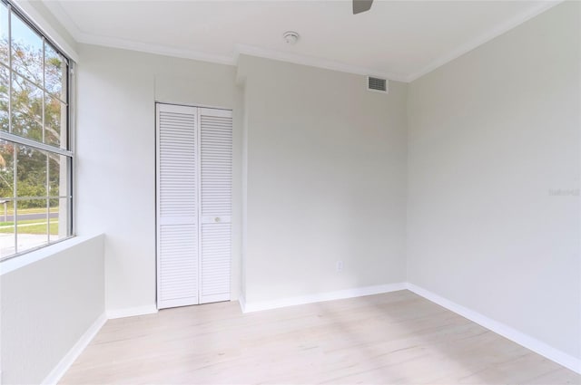 unfurnished bedroom with ceiling fan, ornamental molding, a closet, and light wood-type flooring