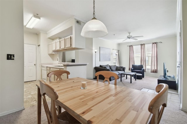 dining space featuring light colored carpet, ceiling fan, and crown molding