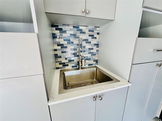 kitchen with backsplash, white fridge, light stone counters, and sink