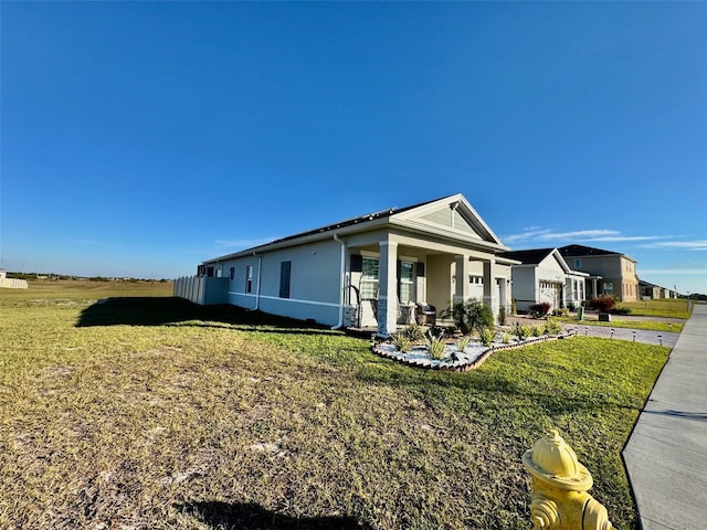 view of side of property featuring covered porch and a lawn