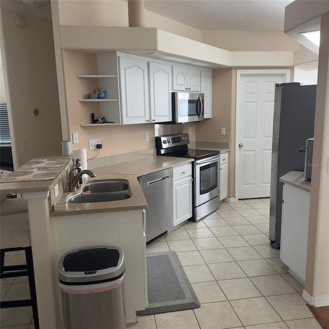 kitchen featuring a breakfast bar, white cabinets, sink, light tile patterned flooring, and stainless steel appliances