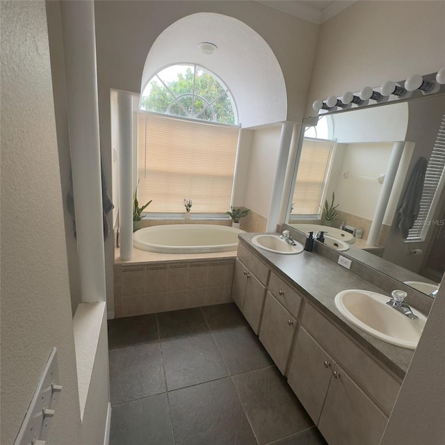 bathroom with tiled tub, tile patterned flooring, and vanity