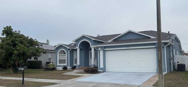 single story home with central AC, a front lawn, and a garage