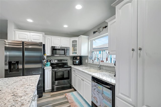 kitchen featuring sink, decorative backsplash, light hardwood / wood-style floors, white cabinetry, and stainless steel appliances