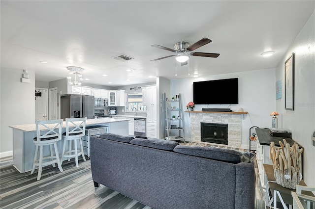 living room with ceiling fan, a fireplace, and wood-type flooring