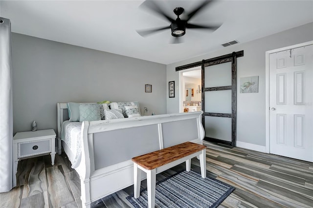 bedroom featuring a closet, a barn door, dark hardwood / wood-style floors, and ceiling fan