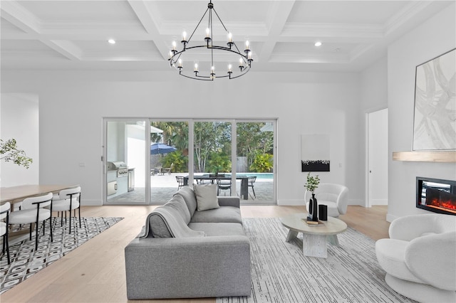 living room featuring an inviting chandelier, beamed ceiling, coffered ceiling, and light wood-type flooring