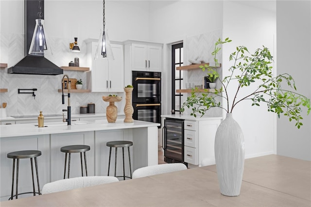 kitchen featuring a breakfast bar area, wine cooler, white cabinetry, and double oven