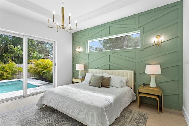 bedroom featuring access to outside, crown molding, an inviting chandelier, and light wood-type flooring