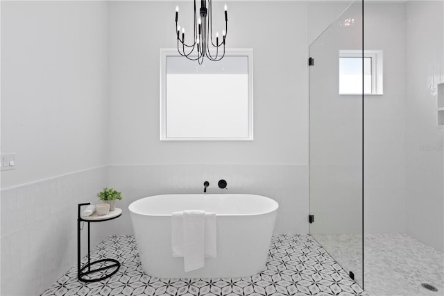 bathroom featuring tile patterned floors, a chandelier, independent shower and bath, and tile walls