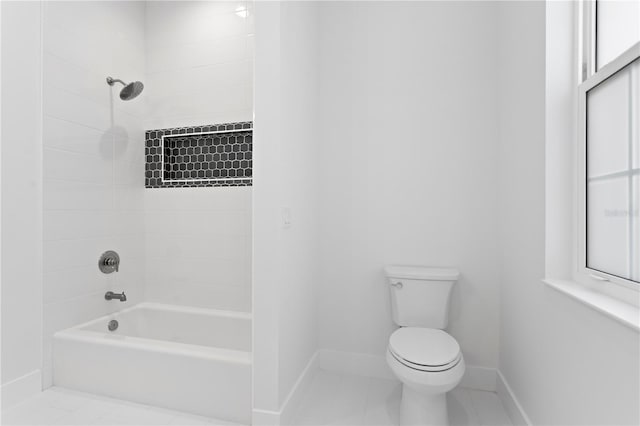 bathroom featuring tile patterned flooring, tiled shower / bath combo, and toilet