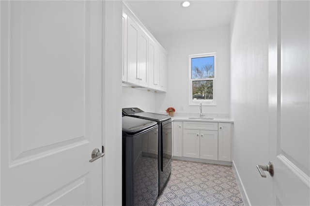 clothes washing area featuring cabinets, washing machine and dryer, and sink