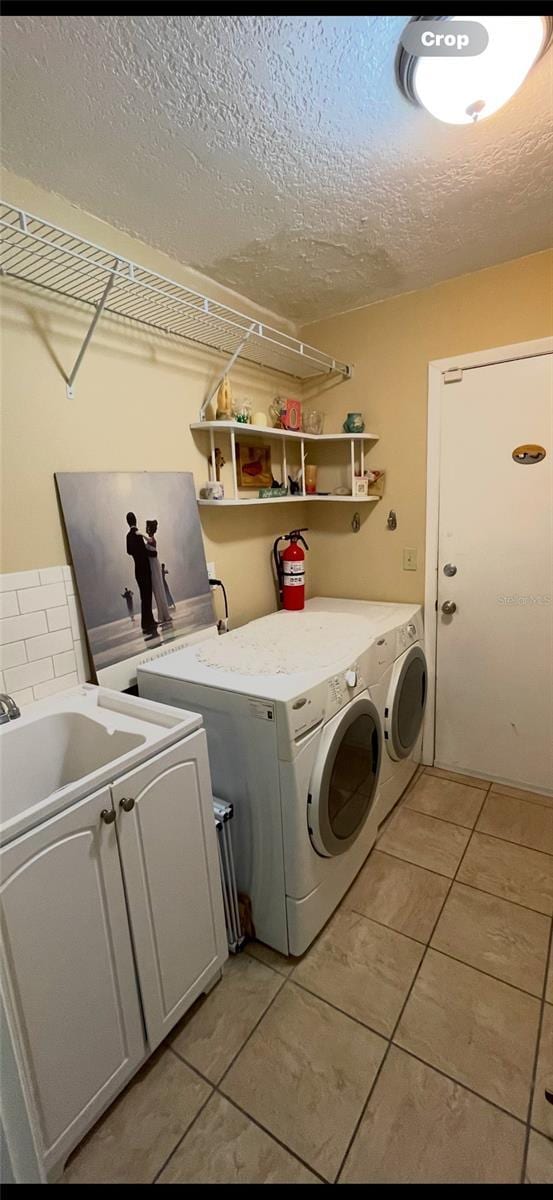 clothes washing area with light tile patterned flooring, cabinets, and washer and clothes dryer