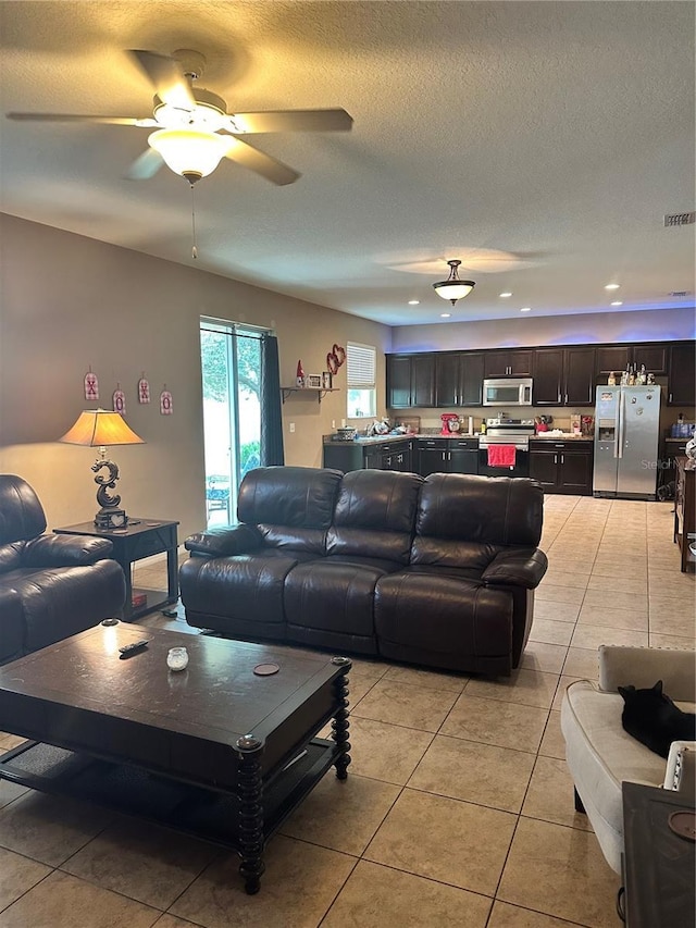 tiled living room with ceiling fan and a textured ceiling