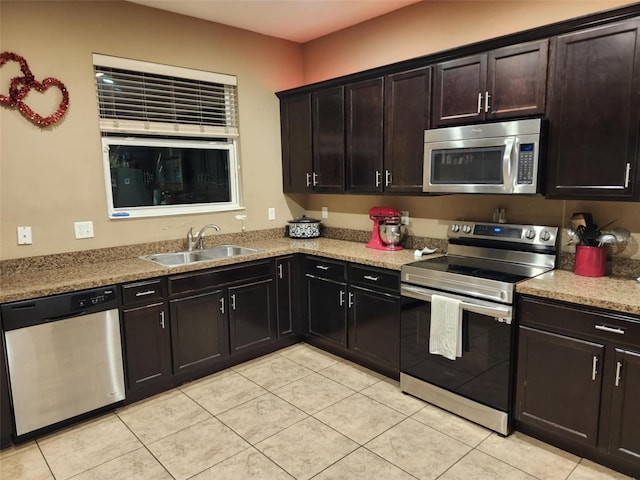 kitchen featuring stainless steel appliances, sink, light tile patterned floors, and dark brown cabinetry