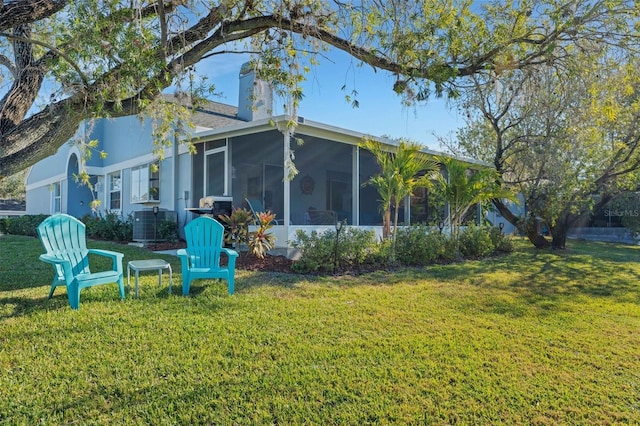 rear view of property featuring a sunroom and a yard