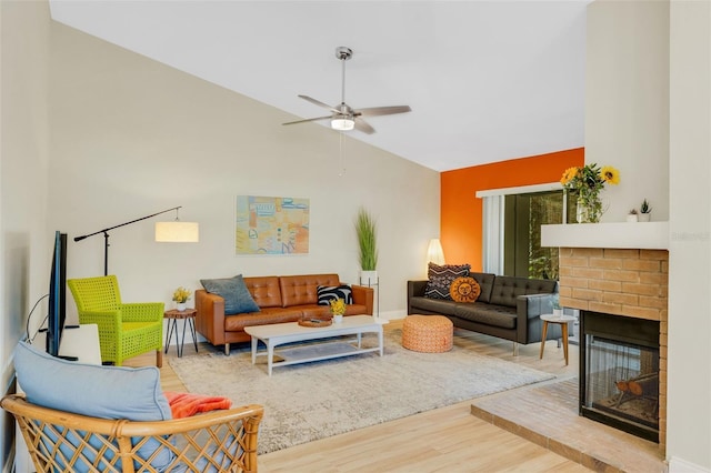 living room with ceiling fan, hardwood / wood-style floors, vaulted ceiling, and a brick fireplace