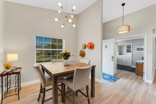 dining area featuring a chandelier, high vaulted ceiling, and light hardwood / wood-style flooring