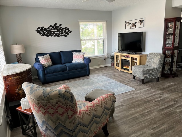 living room featuring ceiling fan, a textured ceiling, and hardwood / wood-style flooring