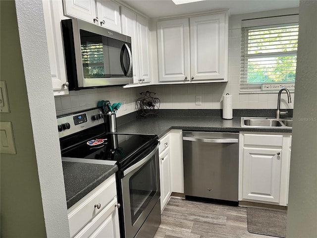 kitchen with light wood-type flooring, tasteful backsplash, stainless steel appliances, sink, and white cabinetry