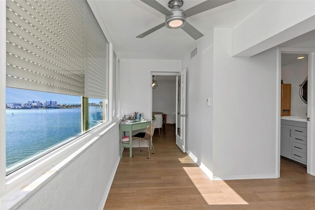 corridor with light hardwood / wood-style floors and a water view