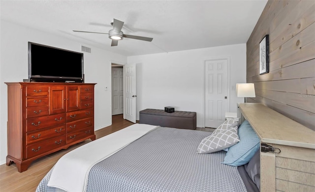 bedroom featuring ceiling fan, hardwood / wood-style floors, and wood walls