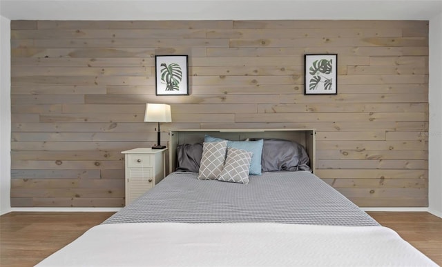 bedroom featuring hardwood / wood-style floors and wooden walls