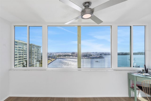 interior space featuring a wealth of natural light, ceiling fan, and a water view