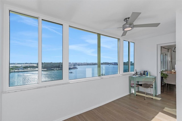 unfurnished sunroom with ceiling fan and a water view