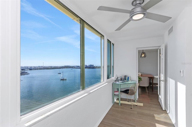 sunroom / solarium featuring ceiling fan and a water view