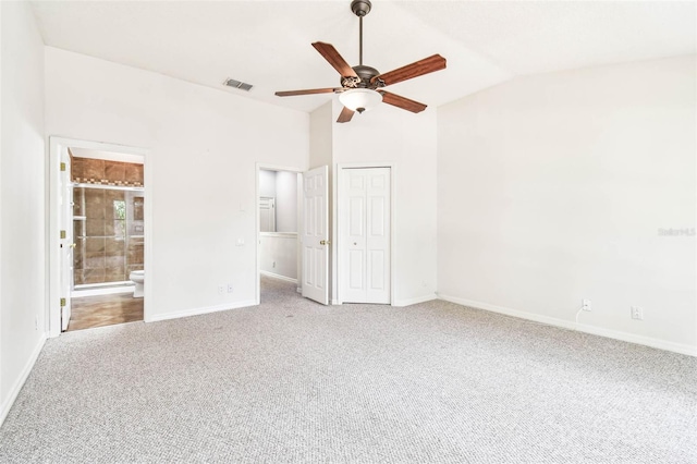 unfurnished bedroom featuring carpet flooring, ceiling fan, vaulted ceiling, and ensuite bath