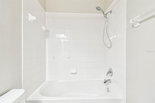 bathroom with tiled shower / bath combo and toilet