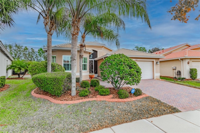 view of front of home with stucco siding, an attached garage, a tile roof, and decorative driveway