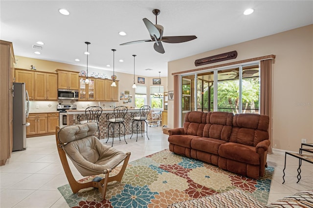 tiled living room with ceiling fan and a healthy amount of sunlight