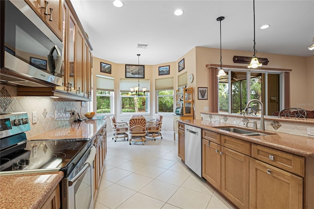 kitchen with decorative backsplash, light stone countertops, stainless steel appliances, sink, and pendant lighting