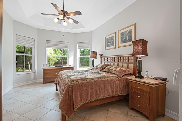 tiled bedroom featuring a tray ceiling and ceiling fan